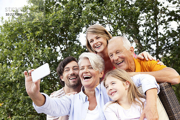 Glückliche Großfamilie beim Fotografieren von Handys im Freien