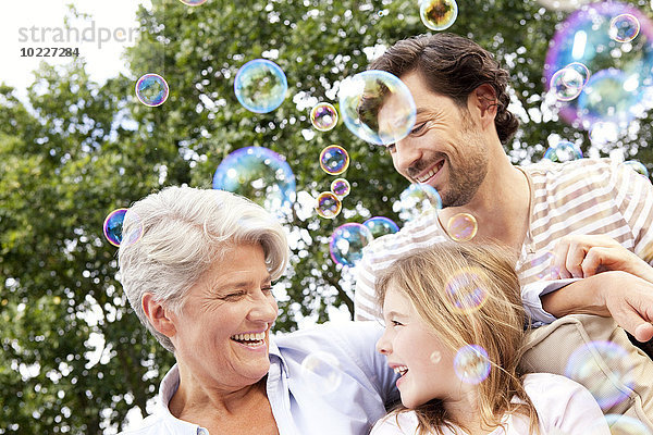 Glückliche Großmutter  Vater und Mädchen umgeben von Seifenblasen