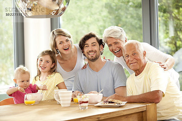 Porträt einer glücklichen Großfamilie am Frühstückstisch