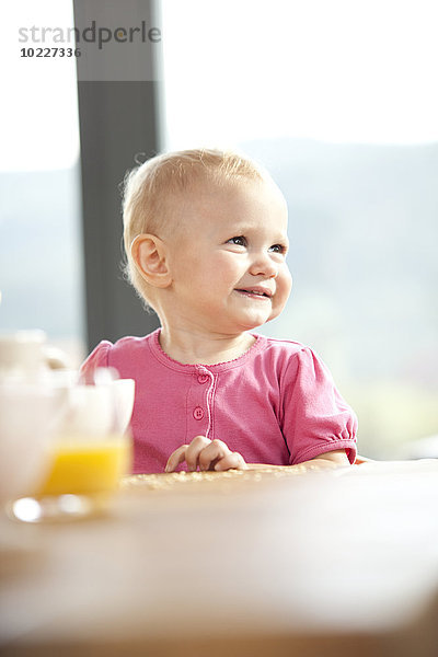 Lächelndes Baby am Frühstückstisch