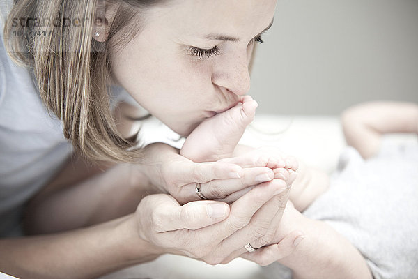 Junge Mutter küsst Fuß des Mädchens