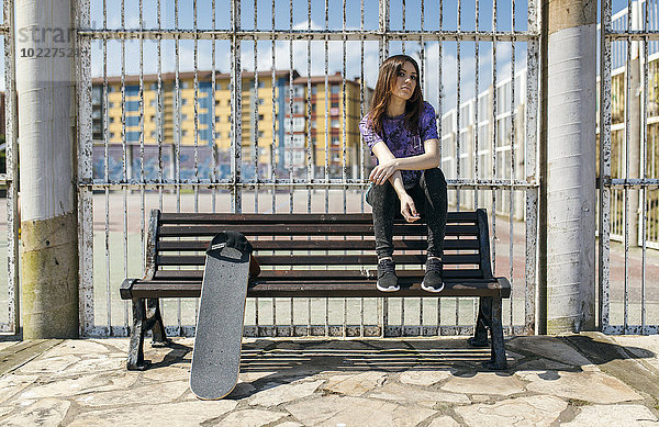 Spanien  Gijon  Skateboarderin auf der Rückenlehne einer Bank sitzend