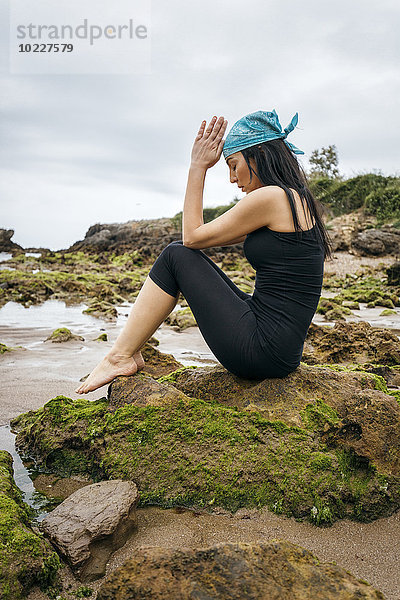 Spanien  Asturien  Gijon  Frau beim Yoga an einem Felsenstrand