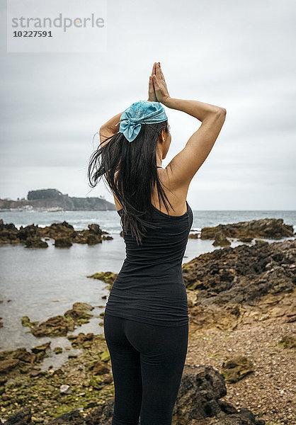 Spanien  Asturien  Gijon  Frau beim Yoga an einem Felsenstrand