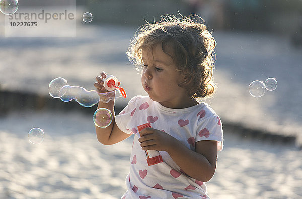 Kleines Mädchen macht Seifenblasen auf dem Spielplatz