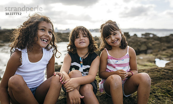 Spanien  Gijon  Gruppenbild von drei kleinen Kindern an der Felsenküste