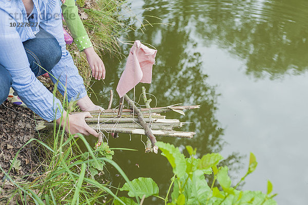 Deutschland  Frau legt Spielzeugfloss ins Wasser