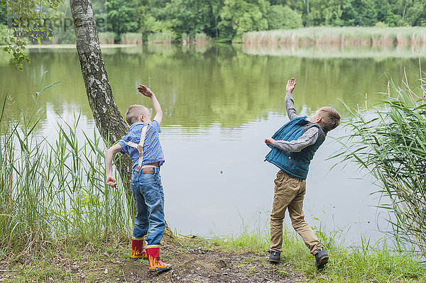 Deutschland  Jungen am Teich werfen Steine