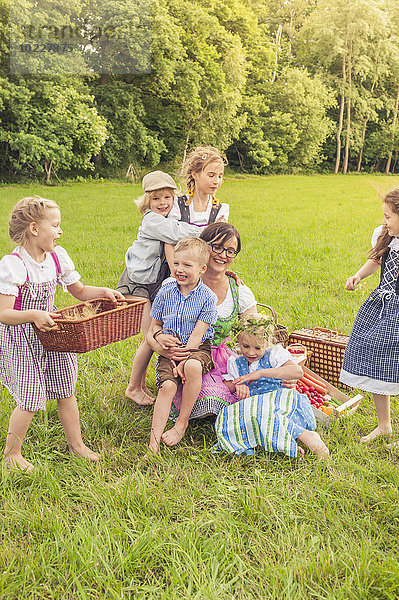 Deutschland  Sachsen  Kinder und deren Erzieher in traditioneller Kleidung auf einer Wiese