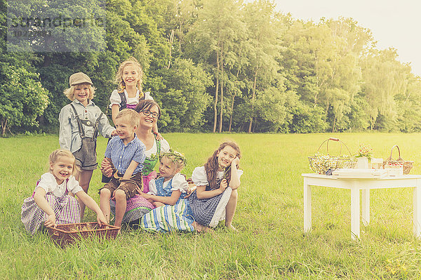 Deutschland  Sachsen  Gruppenbild von Kindern in traditioneller Kleidung und ihrem Erzieher auf einer Wiese