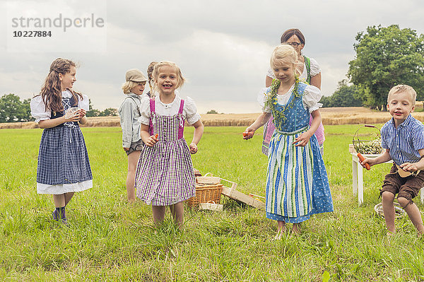 Deutschland  Sachsen  Kinder in traditioneller Kleidung tanzen auf einer Wiese