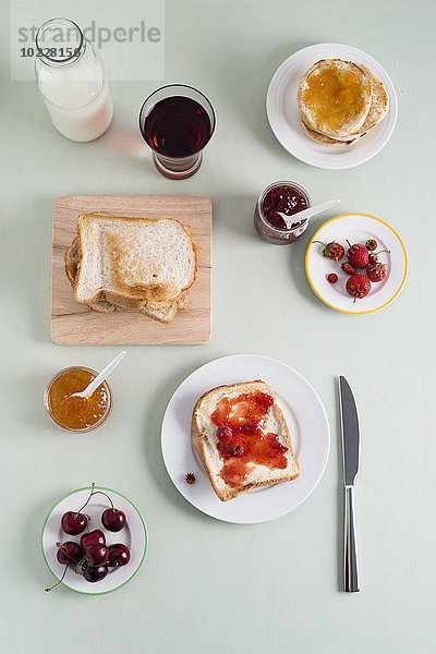 Toast mit Erdbeermarmelade  Toast mit Aprikosenmarmelade  Erdbeeren und Kirschen  Milchflasche