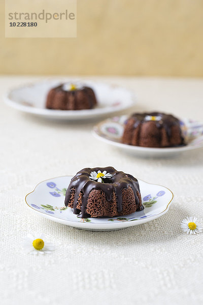 Mini-Schokoladenkuchen mit essbaren Blumen auf Tellern