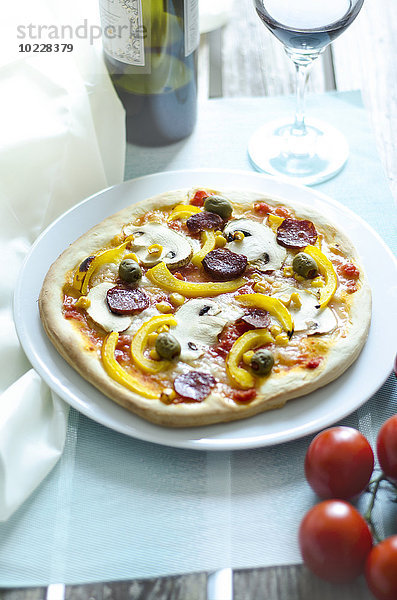 Hausgemachte Pizza mit Champignons  gelber Paprika  Tomaten  grünen Oliven  Chorizo und Rotwein