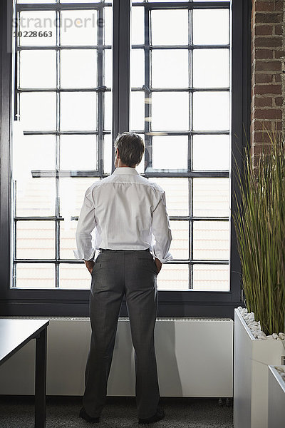 Geschäftsmann im Büro mit Blick aus dem Fenster