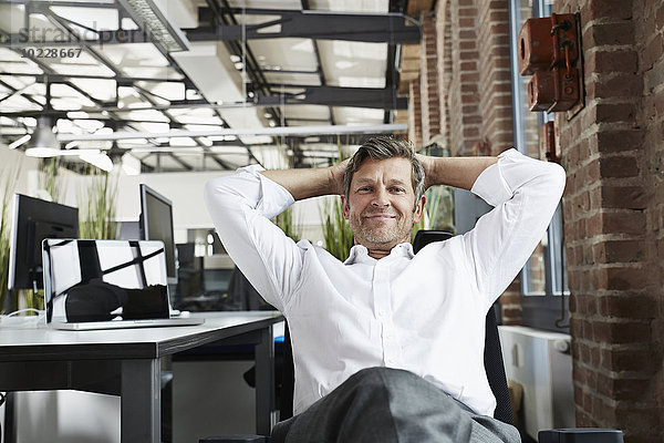 Porträt eines lächelnden Geschäftsmannes im Büro zum Entspannen