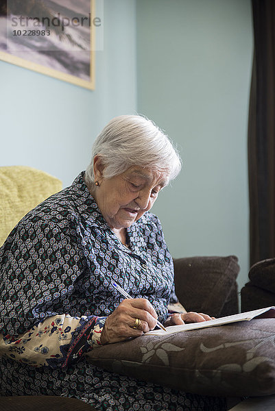 Seniorin beim Kreuzworträtselspiel zu Hause