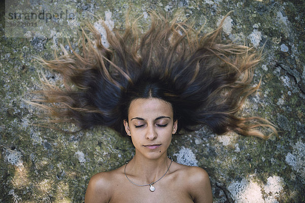 Bildnis einer jungen Frau auf einem Felsen liegend mit zerzaustes Haar und geschlossenen Augen