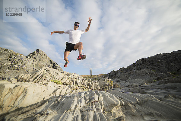 Spanien  Valdovino  junger Mann springt in der Luft in felsiger Landschaft