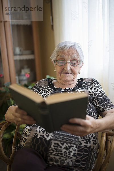 Seniorin beim Lesen eines Buches zu Hause