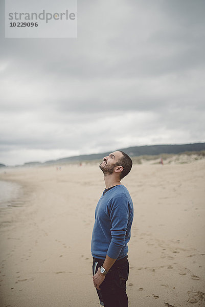 Spanien  Ferrol  Mann steht am Strand und schaut nach oben.