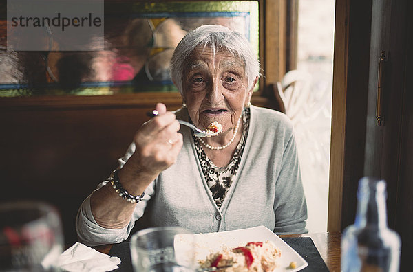 Porträt einer lächelnden Seniorin beim Essen in einem Restaurant