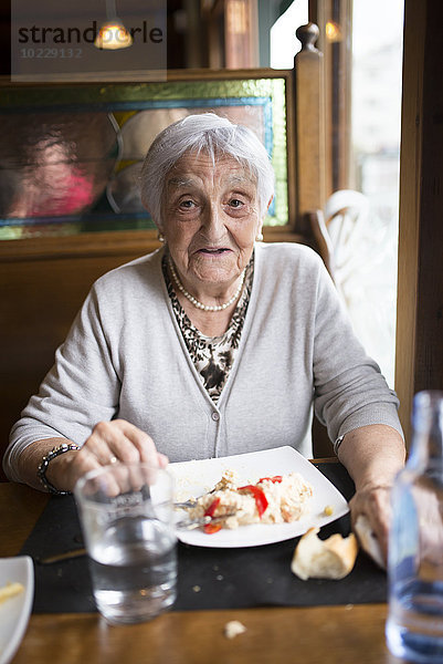 Porträt einer älteren Frau beim Essen in einem Restaurant