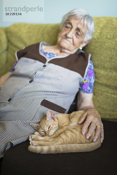 Tabby Kätzchen snoozing neben alter Frau auf der Couch zu Hause