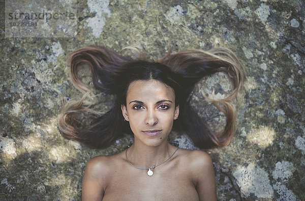 Porträt einer jungen Frau auf einem Felsen liegend