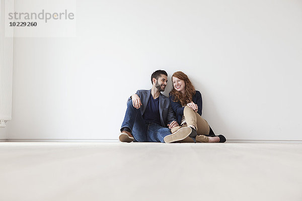 Junges Paar auf dem Boden der neuen Wohnung sitzend