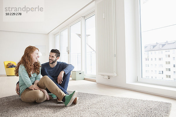 Junges Paar auf dem Boden des Wohnzimmers sitzend