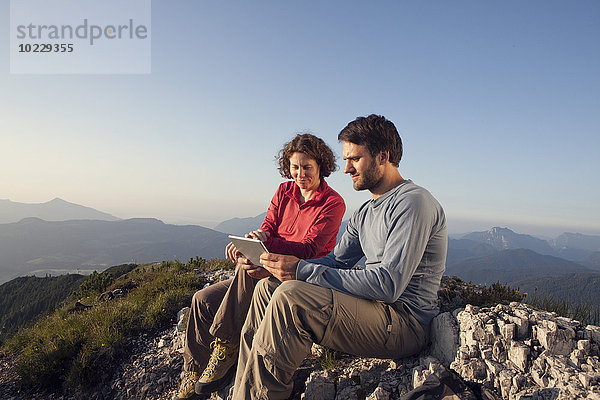 Österreich  Tirol  Unterberghorn  zwei Wanderer sitzend mit digitalem Tablett in alpiner Landschaft