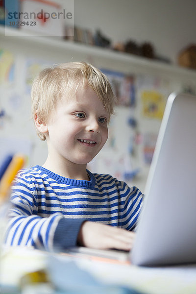 Portrait eines lächelnden kleinen Jungen mit Laptop