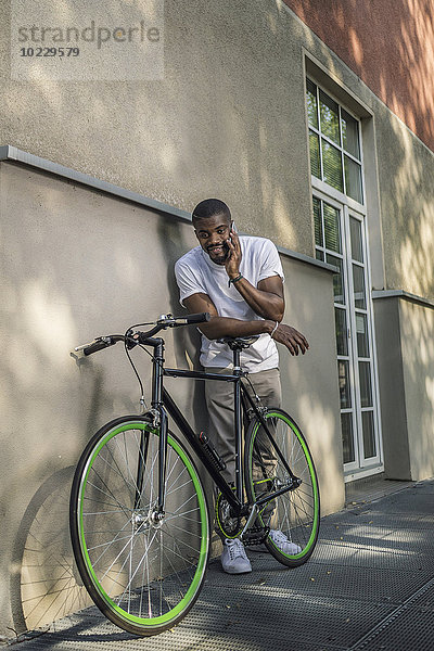 Portrait eines jungen Mannes mit Fahrradtelefonie mit Smartphone