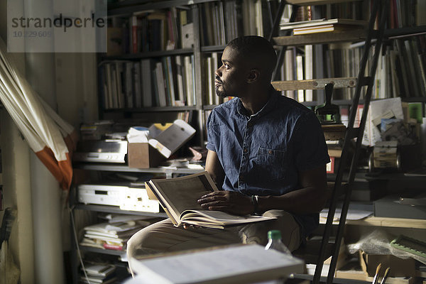 Junger Mann mit Buch im Atelier