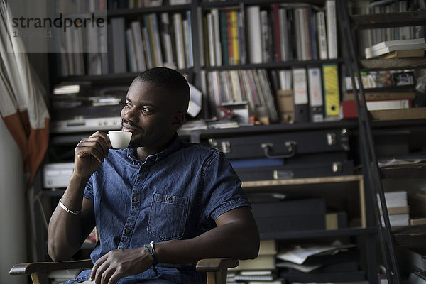 Junger Mann trinkt Kaffee in seinem Atelier