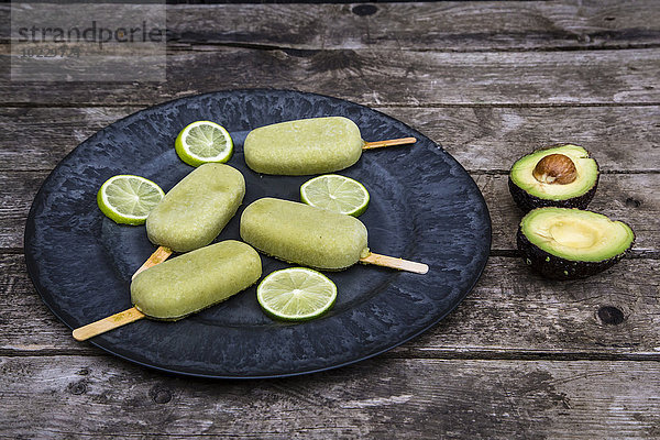 Teller mit Avocado-Eis-Lollies und Limettenscheiben