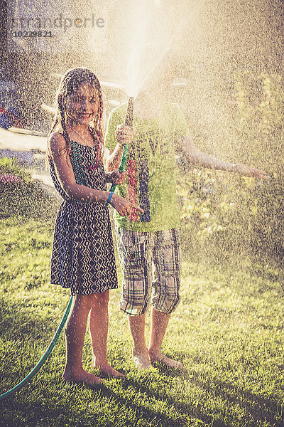 Zwei Kinder planschen mit Wasser im Garten