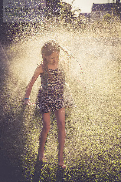 Mädchen hat Spaß mit Spritzwasser im Garten