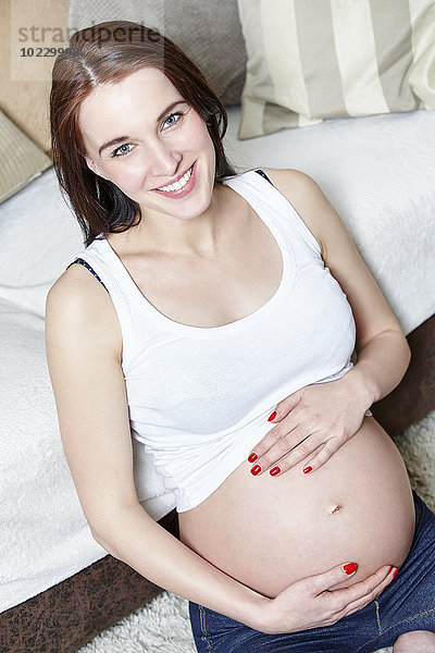 Porträt einer schwangeren Frau  die ihren Bauch hält