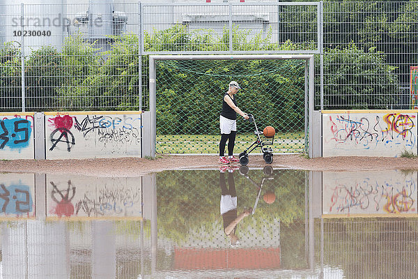 Seniorin mit Rollator auf dem Sportplatz