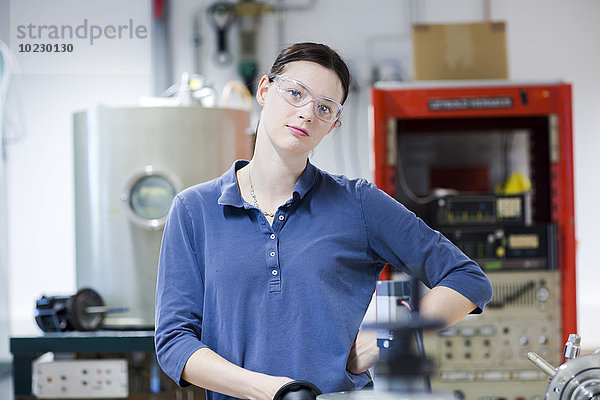 Porträt einer jungen Frau mit Schutzbrille in der Werkstatt