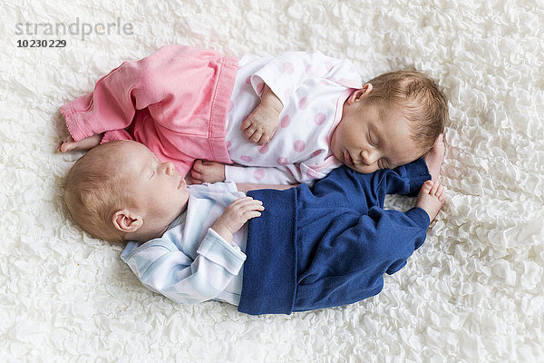 Neugeborene Zwillinge schlafen auf weißer Decke