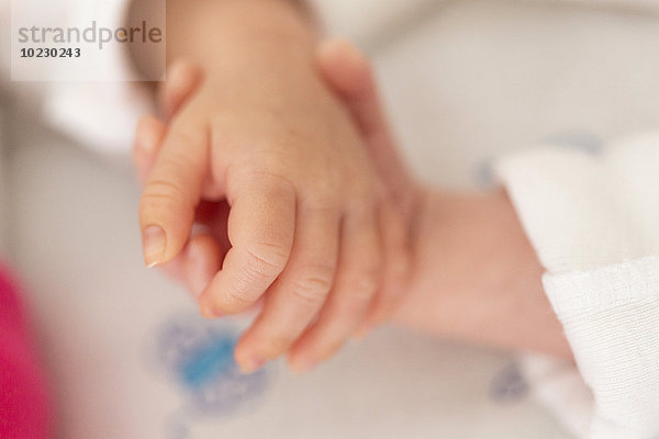 Neugeborene Zwillinge schlafen Hand in Hand  Nahaufnahme