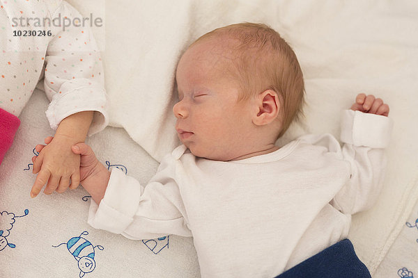 Neugeborene Zwillinge schlafen Hand in Hand