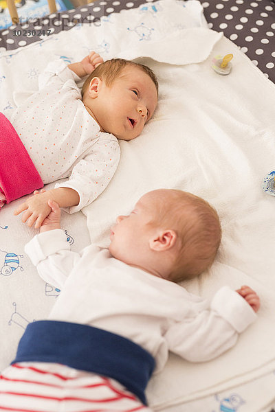 Neugeborene Zwillinge schlafen Hand in Hand