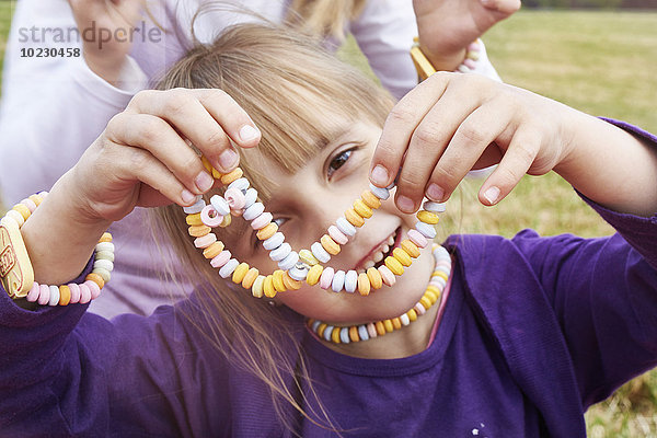 Kleines Mädchen mit Halskette und Armband aus Hunderten und Tausenden von Menschen