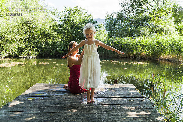Mädchen mit Mutter am Steg am See