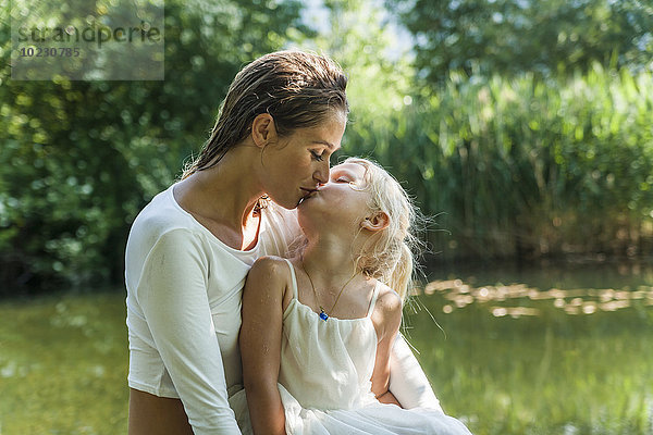 Mutter und Tochter beim Küssen am See