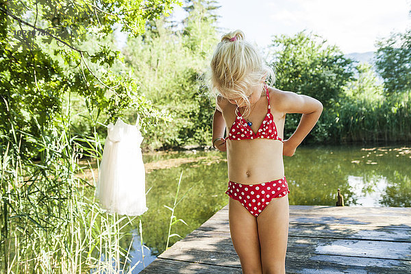 Mädchen im Bikini stehend am Steg am See
